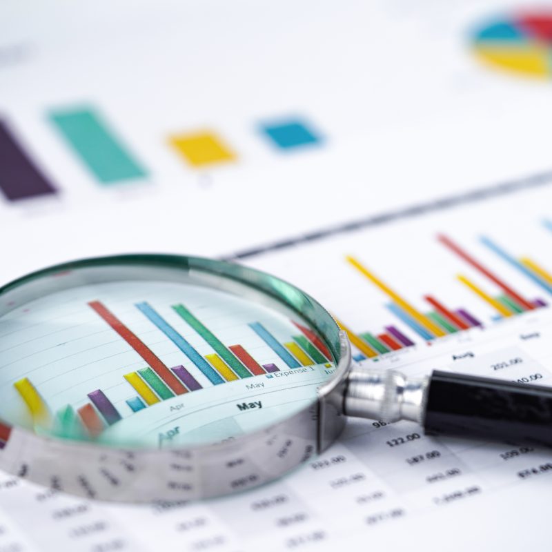 Magnifying glass on charts graphs spreadsheet paper. Financial development, Banking Account, Statistics, Investment Analytic research data economy, Stock exchange trading, Business office company meeting concept.